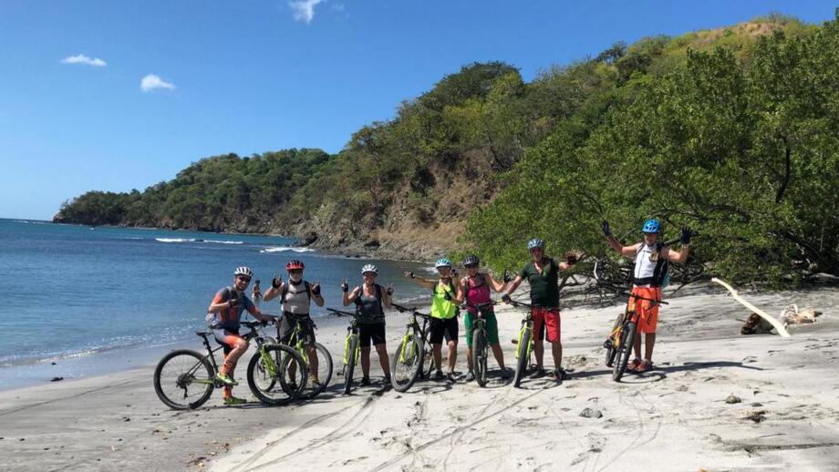 Eine MTB-Gruppe in Costa Rica am Strand. Die Sonne scheint.