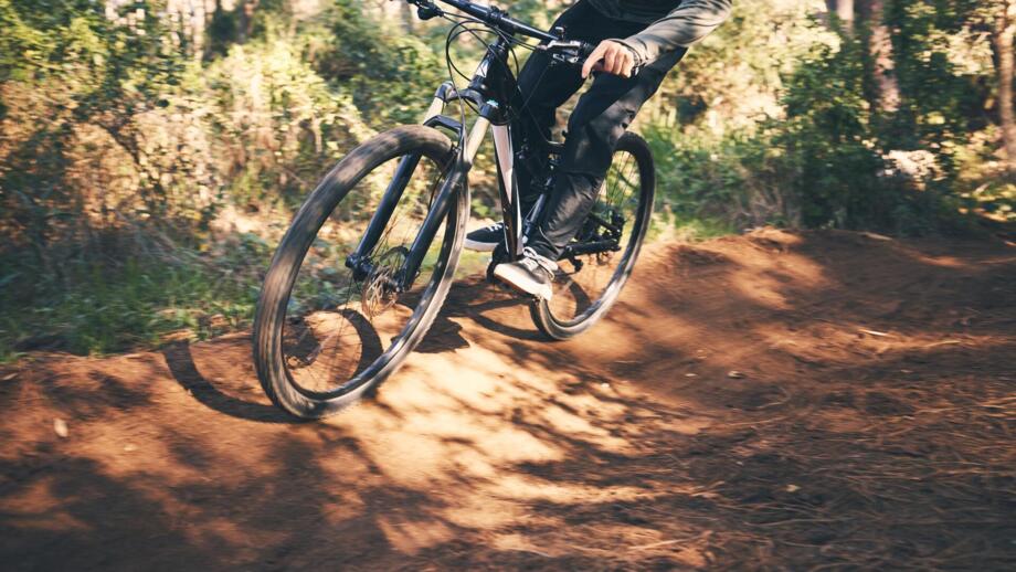 Ein Mountainbiker unterwegs im Wald auf einem Trail beim Fahrtechniktraining.