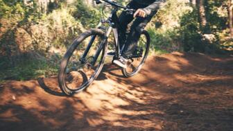 Ein Mountainbiker unterwegs im Wald auf einem Trail beim Fahrtechniktraining.