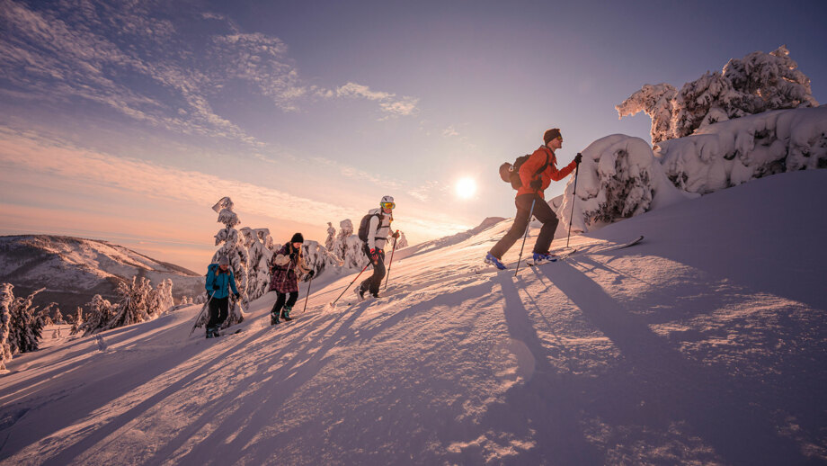 Skitourengruppe im Schnee bei Sonnenuntergang