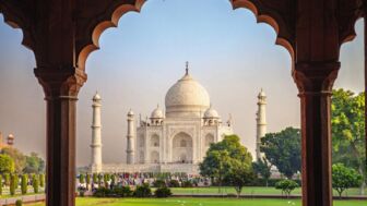 Agra Taj Mahal aus weißem Marmor mit vier Minaretten und grüner Gartenanlage im Vordergrund