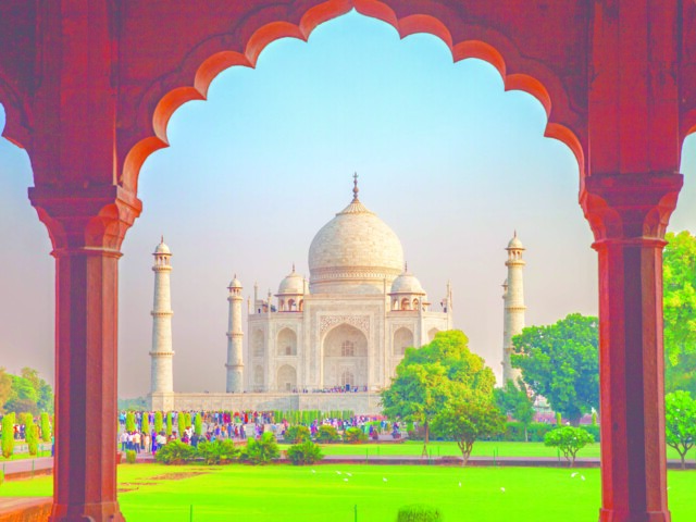 Taj Mahal in Agra Mausoleum mit Kuppel und vier Minaretten aus weißem Marmor, im Vordergrund Gartenanlage, dahinter Besucher