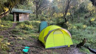 Ein Zelt im Cave Camp auf der Umbwe Route im Kilimandscharo Nationalpark mit dahintreliegendem Toilettenzelt