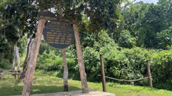 Das Umbwe Gate Schild am Eingang vom Kilimandscharo Nationalpark zur Umbew Route umgeben von üppigem Grün