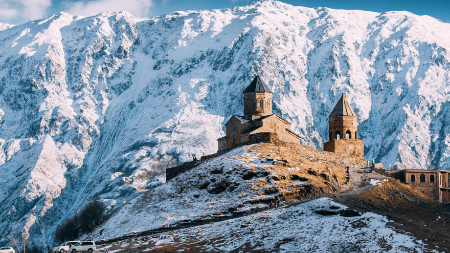 Wallfahrtskirche Gergeti vor den tiefverschneiten flanken des Fünftausenders Kasbek in Georgien