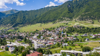 Blick auf ein Dorf am Berg an einem sonnigen Tag, grüne Landschaft