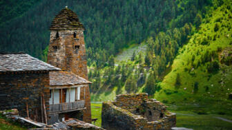 Steinernes Wohnhaus und alter Wachtturm in grünem Wald- und Wiesengelände in Dartlo, Chewsuretien, Georgien