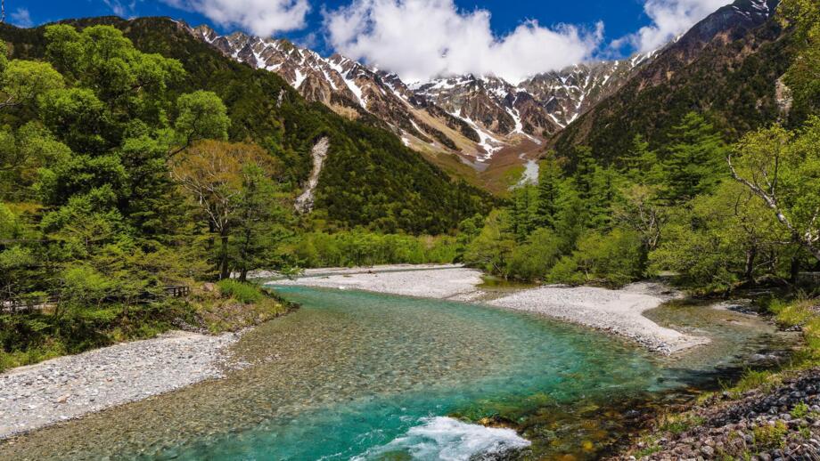 Azusa-Fluss im Kamikochi-Tal in den Japanischen Alpen mit Bäumen und Bergen im Hintergrund