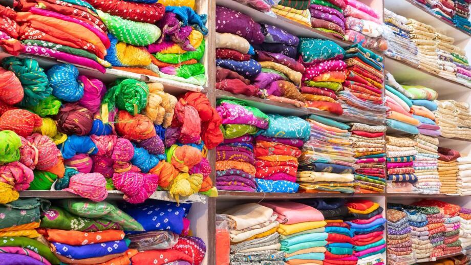 Stoffe in bunten Farben im Regal eines Geschäftes in Rajasthans Hauptstadt Jaipur