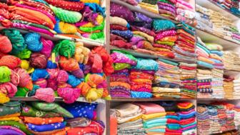 Stoffe in bunten Farben im Regal eines Geschäftes in Rajasthans Hauptstadt Jaipur