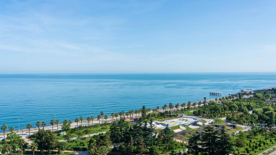 Strandpromenade bei der georgischen Stadt Batumi am Schwarzen Meer mit Palmen und blauem Wasser