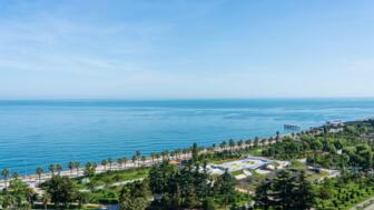 Strandpromenade bei der georgischen Stadt Batumi am Schwarzen Meer mit Palmen und blauem Wasser