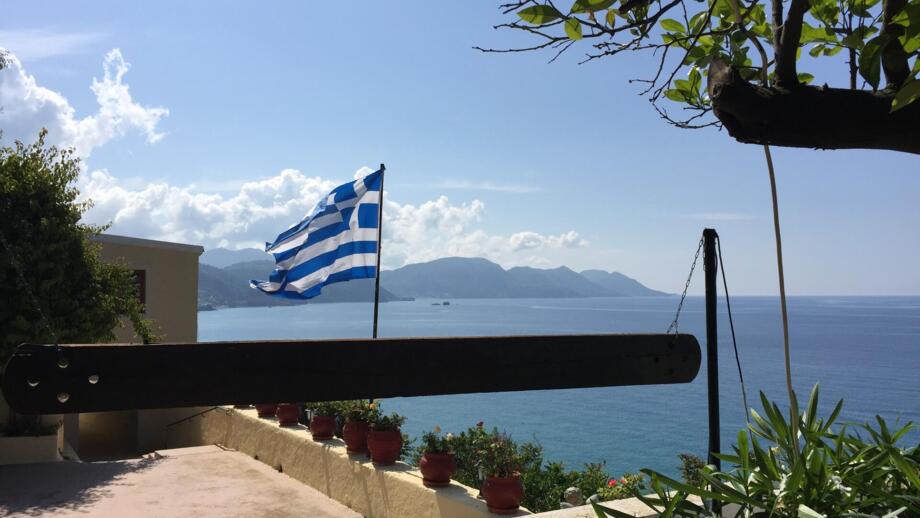 Griechische Flagge vor einer Bucht auf Korfu