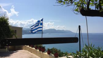 Griechische Flagge vor einer Bucht auf Korfu