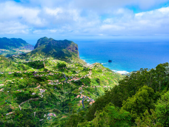 Felskegelan der Küste Madeira mit blauem Meer und grünem Hinterland