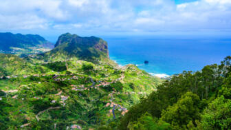 Felskegelan der Küste Madeira mit blauem Meer und grünem Hinterland