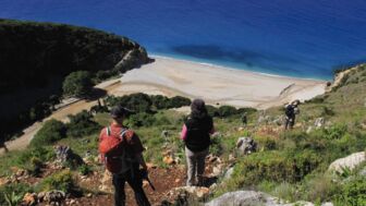 Zwei Wanderer blicken auf eine feinsandige Bucht im Süden von Albanien
