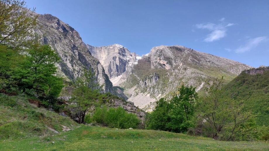 Eine grüne Wiese und im Hintergrund die Felswände der Berge im Süden Albaniens