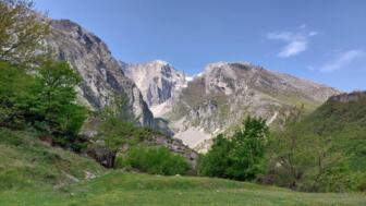 Eine grüne Wiese und im Hintergrund die Felswände der Berge im Süden Albaniens