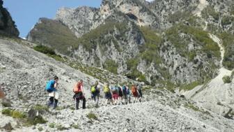 Eine Wandergruppe passiert einen schmalen Pfad umgeben von felsigen Wänden