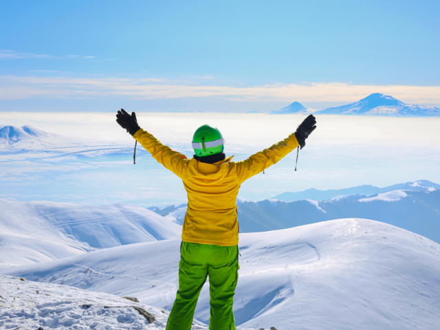Skifahrer in gelber und grüner Bekleidung auf dem Gipfel des Berges Teghenis mit Blick auf den Fünftausender Ararat