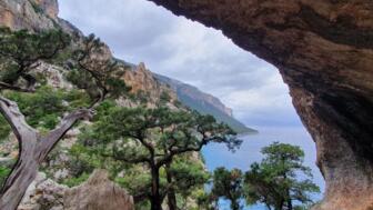 Blick aus einer kleinen Höhle in Richtung felsige Berge und das blaue Meer