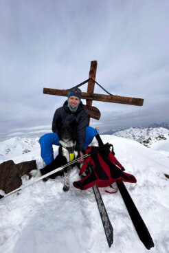 Bergwanderführer Samuel Slanzi mit Hund auf Skitour am Gipfelkreuz