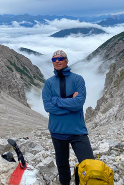 Bergwanderführer Mark Renker umgeben von Bergen mit Wolken im Hintergrund
