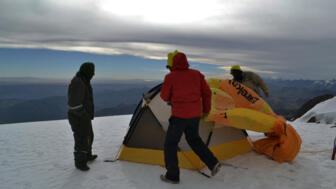 Drei Bergsteiger bauen Zelte auf