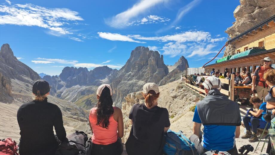 Gruppe von Wanderern, die eine Pause auf einer Terrasse mit Blick auf die Dolomiten machen