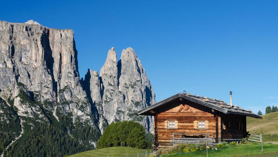 Eine Hütte in grüner Wiese neben Felsen
