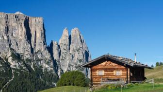 Eine Hütte in grüner Wiese neben Felsen