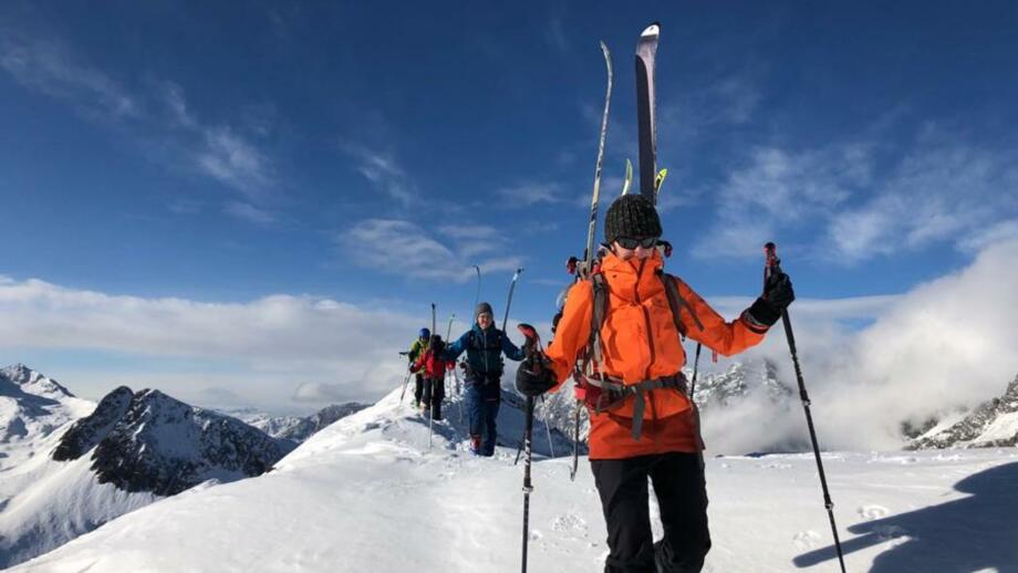 Skitourengeherin auf den letzten Metern zum Gipfel mit Ski am Rucksack