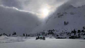 Blick auf die Sonne von der Lizumer Hütte aus, die durch die Wolken blitzt.