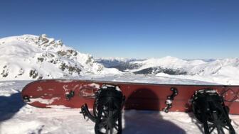 Ein Snowboard vor dem Gipfelpanorama im oberen Wattental auf dem Eiskarjoch.