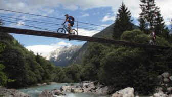 Mountainbiker*in auf einer Brücke beim Überqueren der Soca