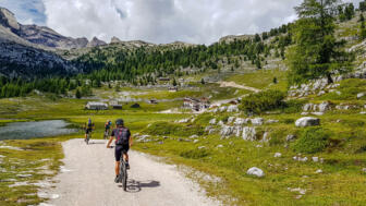 Ein Mountainbiker unterwegs auf der Tour mit der Bergwelt der Dolomiten im Hintergrund.