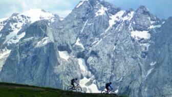 Zwei Mountainbiker unterwegs mit der imposanten Bergwelt der Dolomiten im Hintergrund.