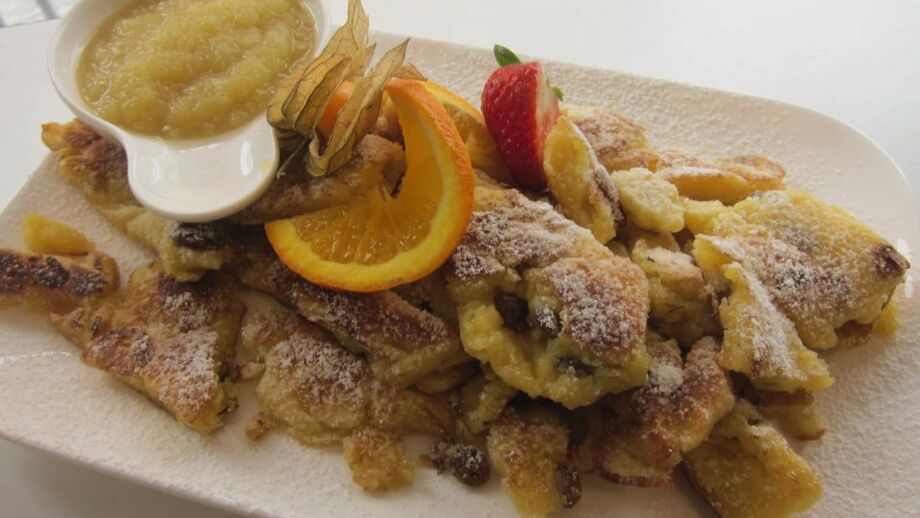 Eine österreichische kulinarische Spezialität serviert auf einem weißen Teller angerichtet mit Apfelmus, der Kaiserschmarrn.
