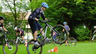 Mountainbiker auf einer Wiese beim Fahren um ein Hindernis.