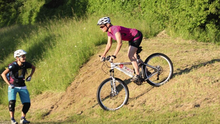 Mountainbikerin auf einer Wiese während des Fahrtechniktraining bei der Bremsübung