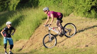 Mountainbikerin auf einer Wiese während des Fahrtechniktraining bei der Bremsübung