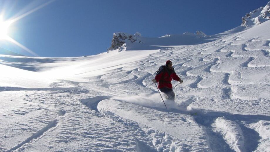 Skifahrer bei der Abfahrt im Powder mit bestem Wetter und bestem Tiefschnee