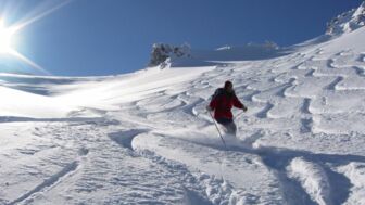 Skifahrer bei der Abfahrt im Powder mit bestem Wetter und bestem Tiefschnee