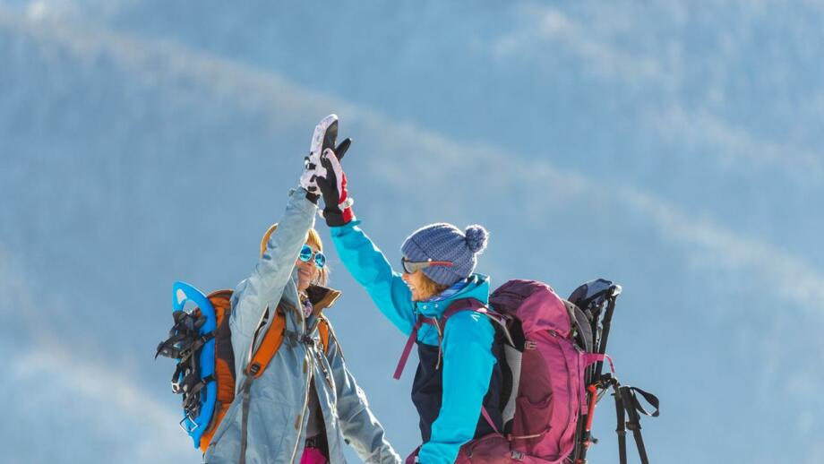 Zwei Schneesschuhgehern in Winterlandschaft, die High Five machen