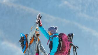 Zwei Schneesschuhgehern in Winterlandschaft, die High Five machen