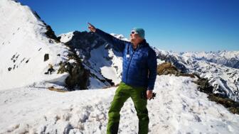 Bergführer am Gipfel bei Sonne und blauem Himmel