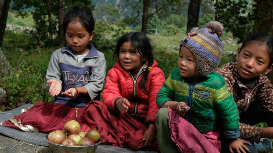 Kleine Kinder im Himalaya vor einer Schüssel mit Äpfeln