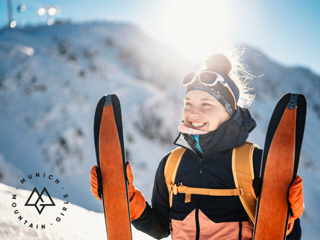 Glückliche Skitourengeherin mit Tourenski im Schnee