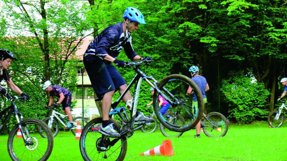 Mountainbiker auf einer Wiese beim Umfahren von Hindernissen.